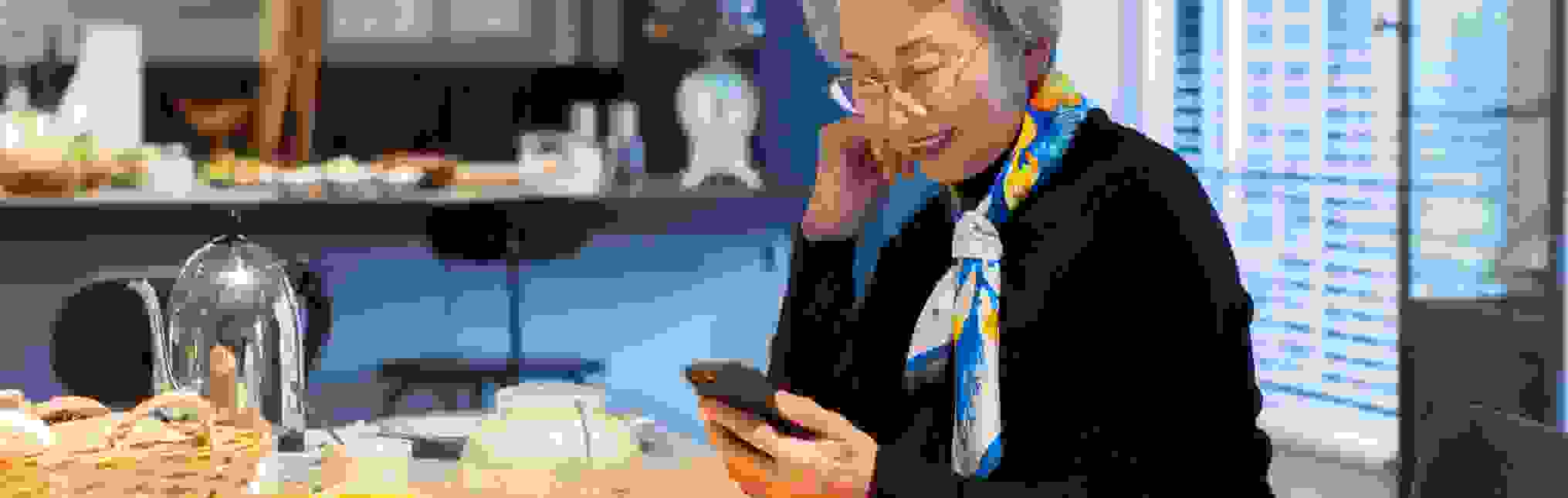 Senior woman operating a smartphone at a cafe
