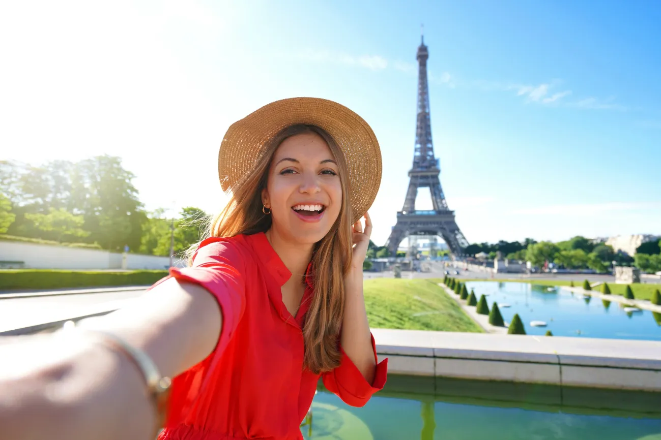 Woman taking a selfie in Paris with the Eiffel Tower behind her