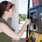Young woman uses her credit card to pay for gasoline at the pump