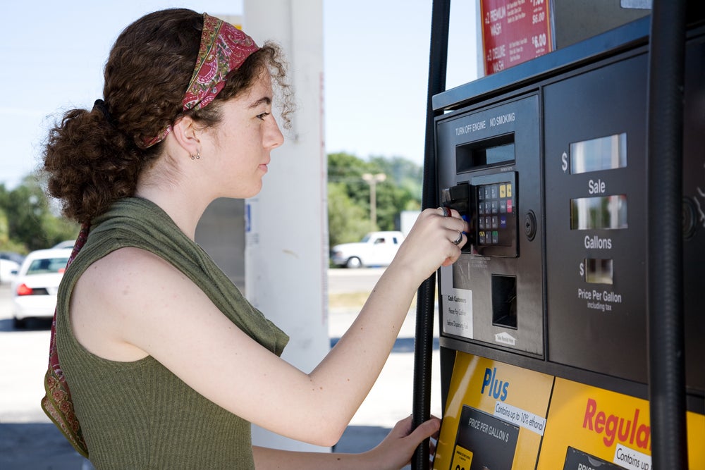 Young woman uses her credit card to pay for gasoline at the pump