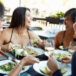 Group Of Female Friends Enjoying Meal Dining At Outdoor Restaurant
