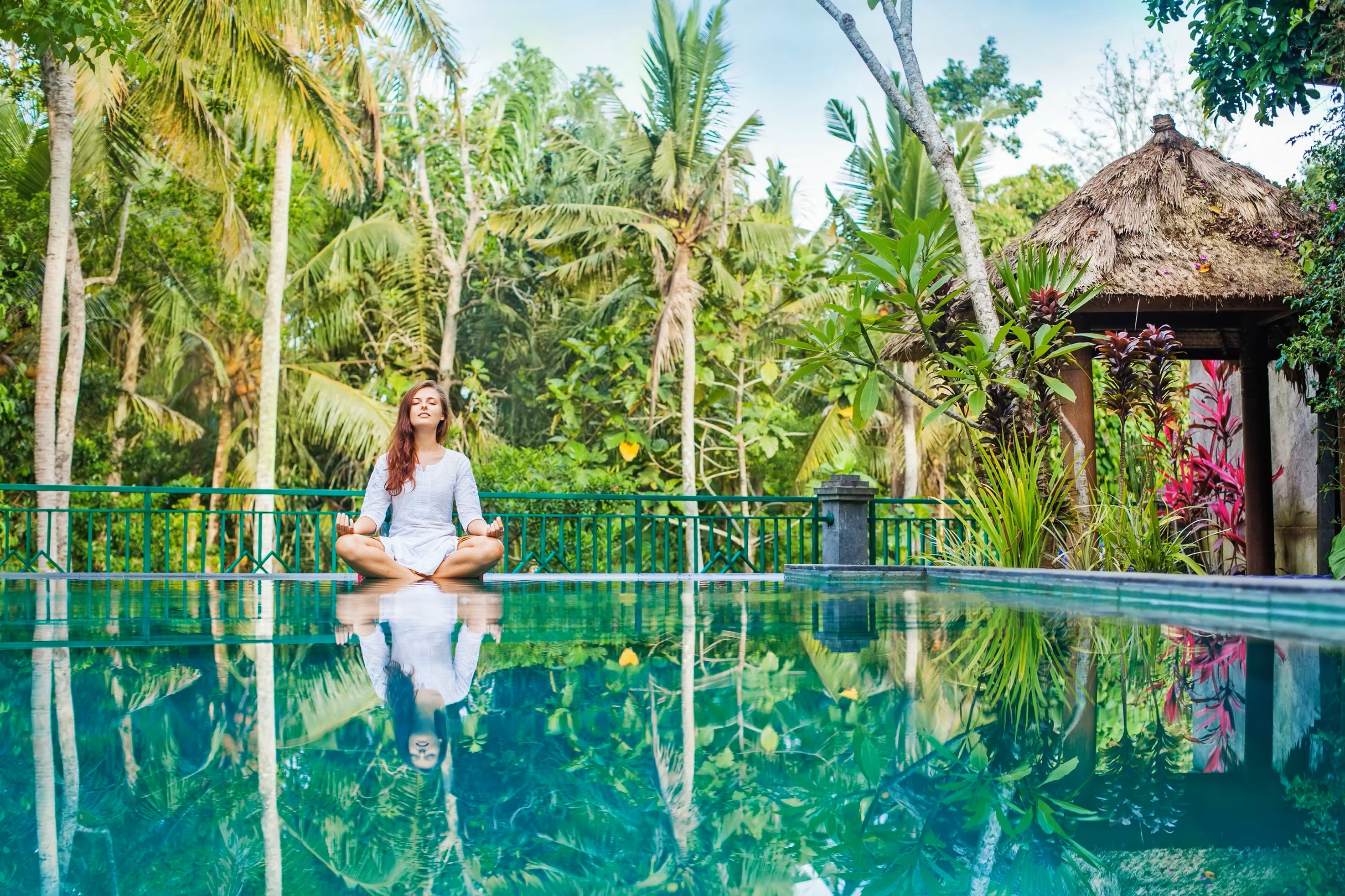 Woman in yoga pose at pool in jungle