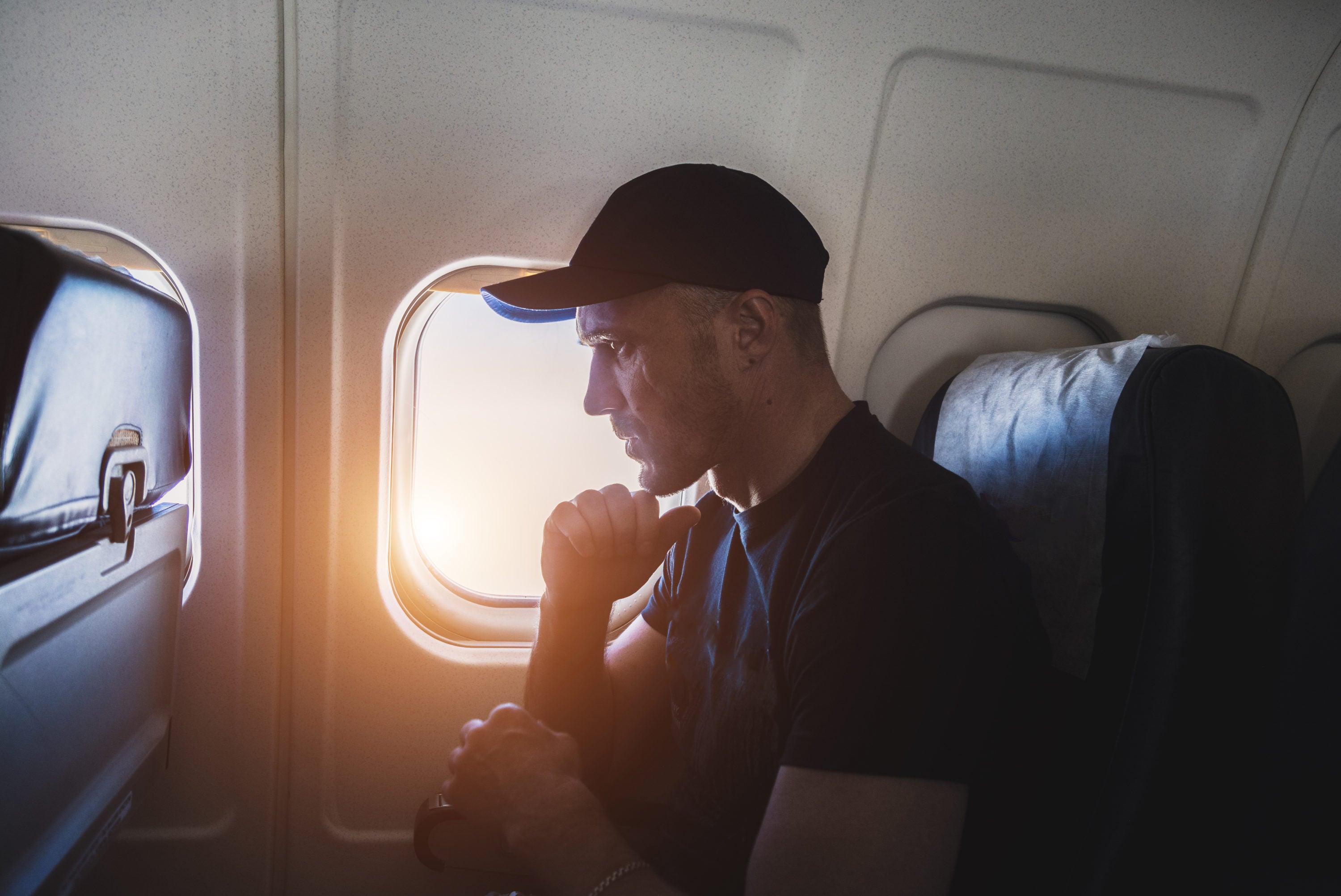 Stressful man sits near the porthole window in an airplane