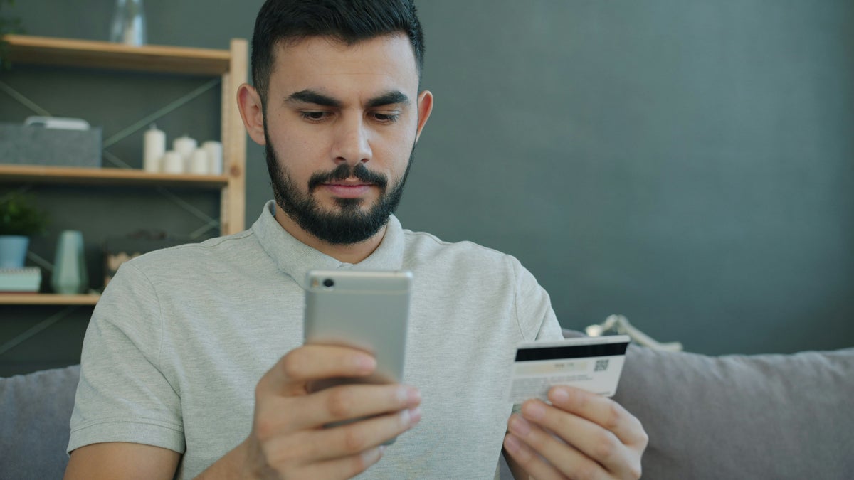Concerned man with credit card looking at phone