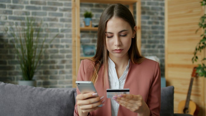 Concerned woman with credit card looking at phone