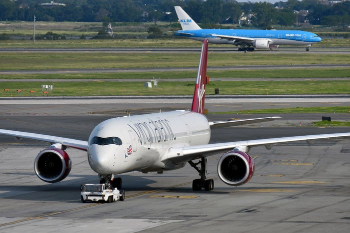 A plane being pushed back by a tractor and another one taxiing in the background