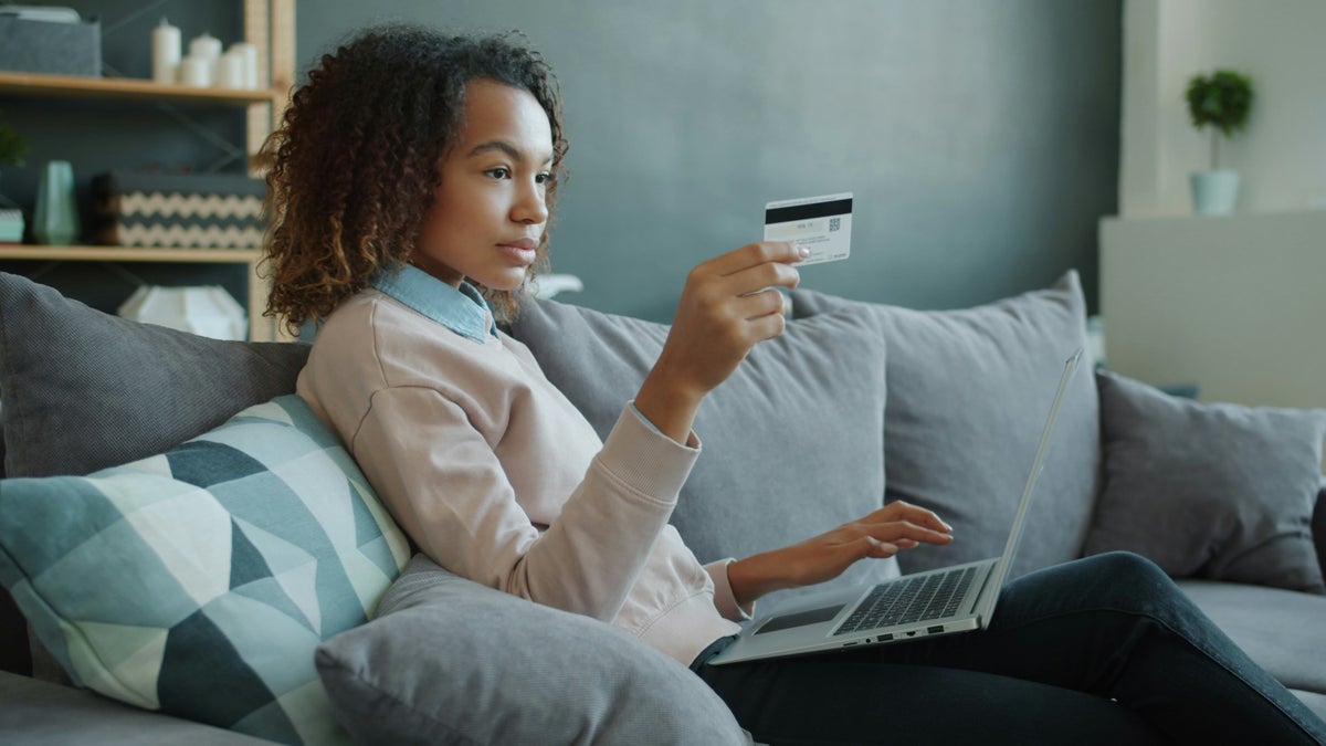 Woman with credit card laptop sofa
