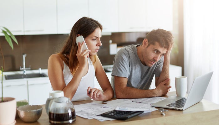 Frustrated couple on phone and laptop computer