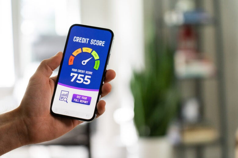 Person holding a smartphone with good credit score meter on the screen