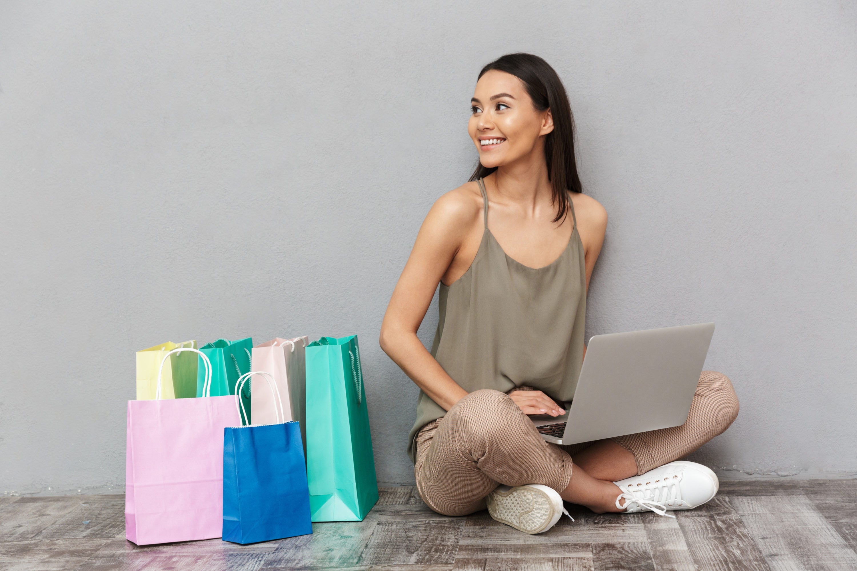 Seated woman shopping on laptop with bags