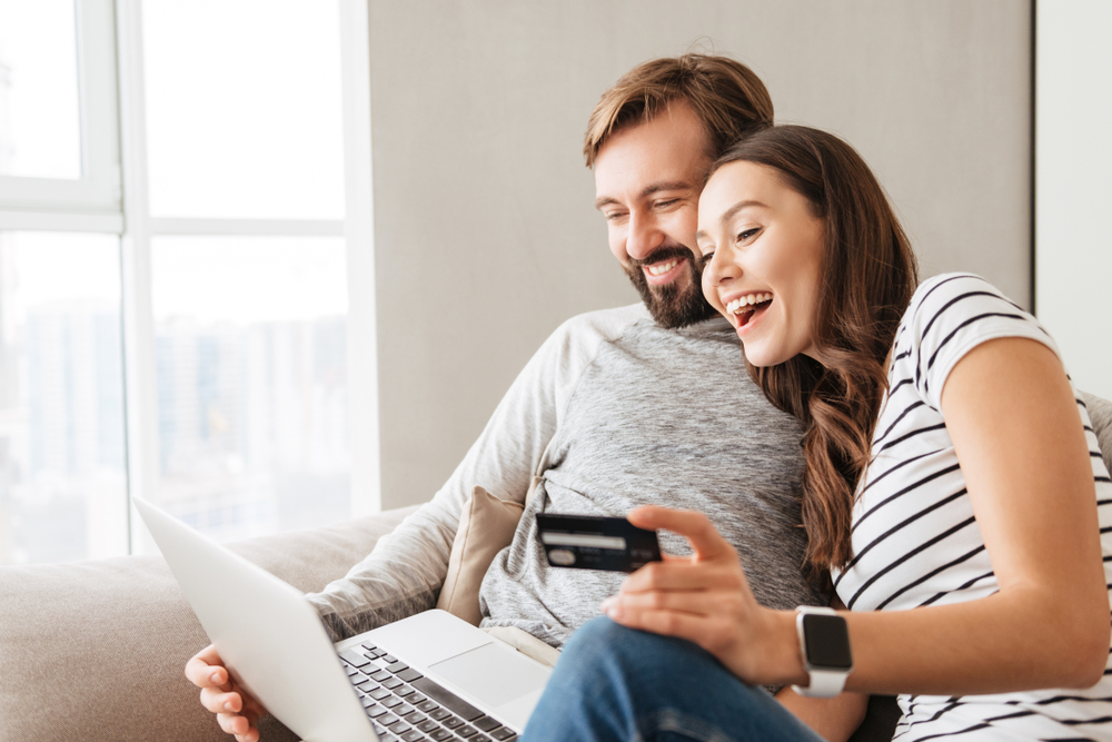 couple smiling shopping online credit card laptop