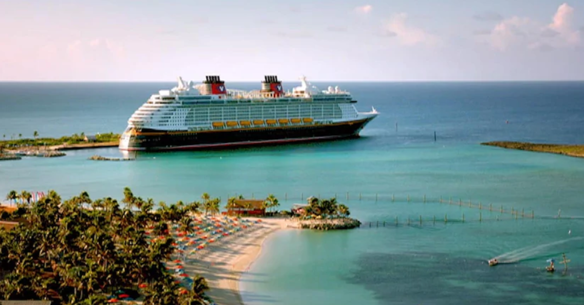 A Disney cruise ship is docked at a small port.