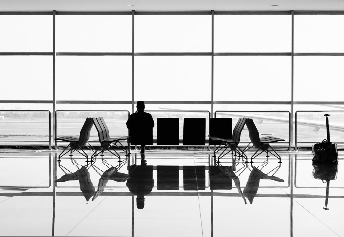 Black and White Photo of a Person Sitting in An Airline Terminal