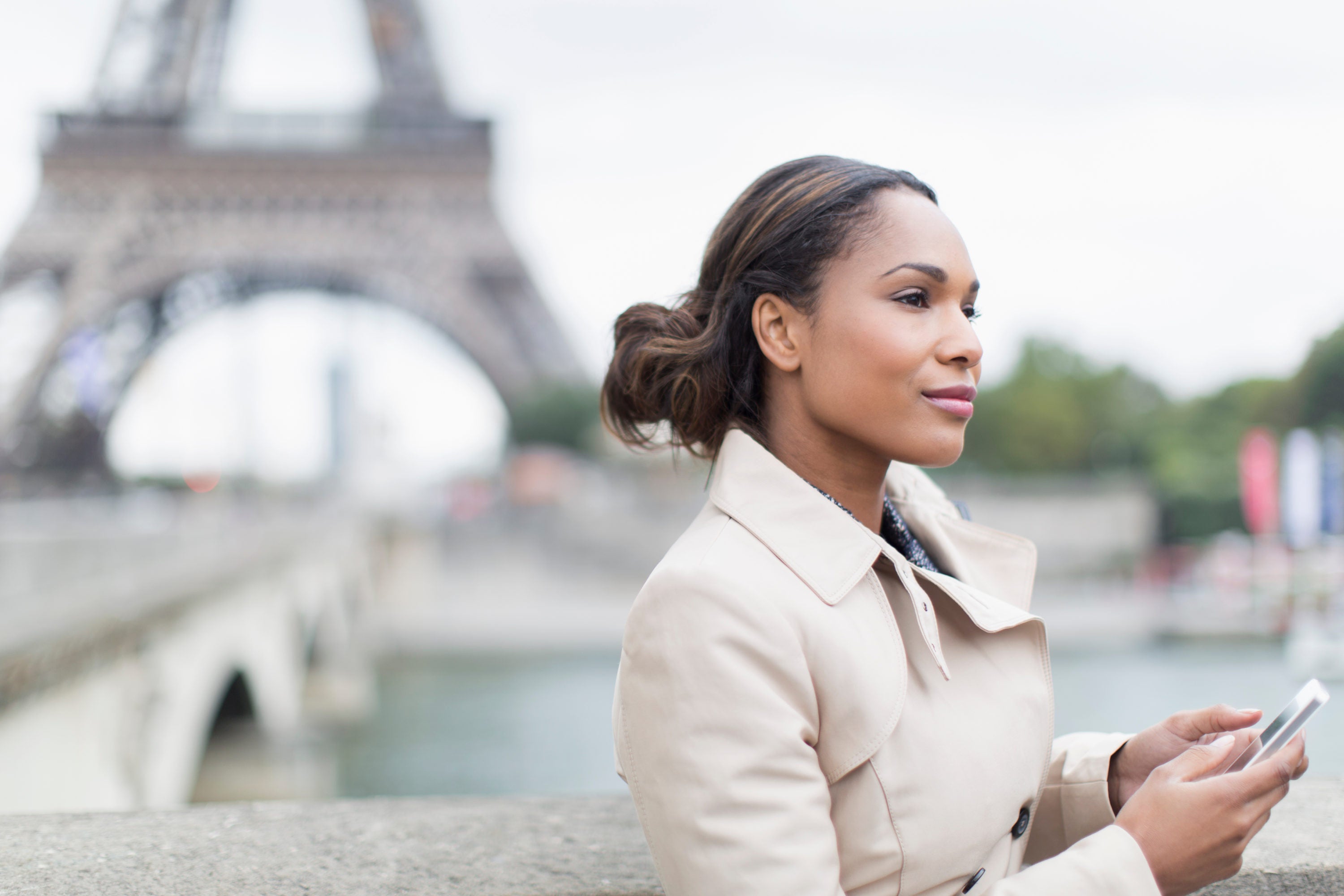 Woman using phone in front of Eiffel Tower
