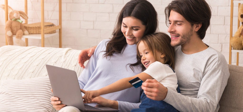 Family girl and parents using laptop with credit card