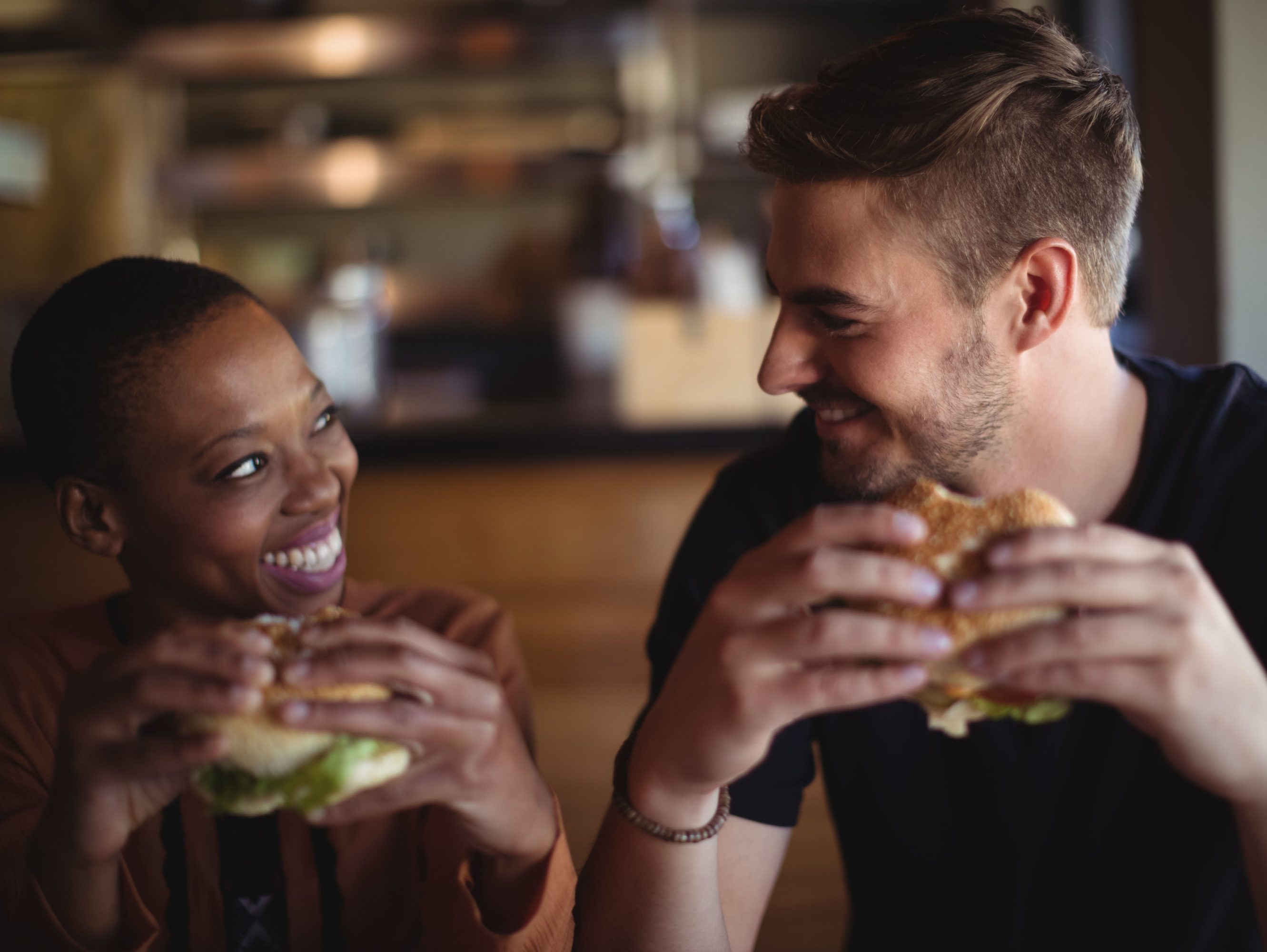 Happy couple having burger in restaurant