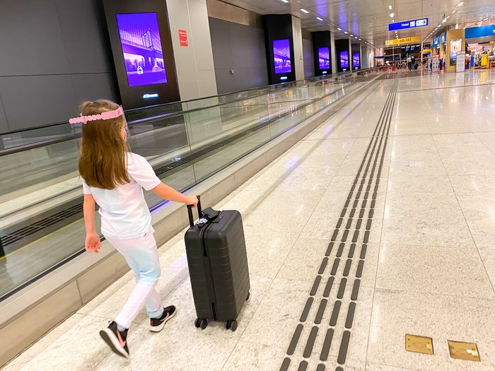 Girl walking with AWAY bag and face mask shield at GRU Guarulhos International Airport Brazil