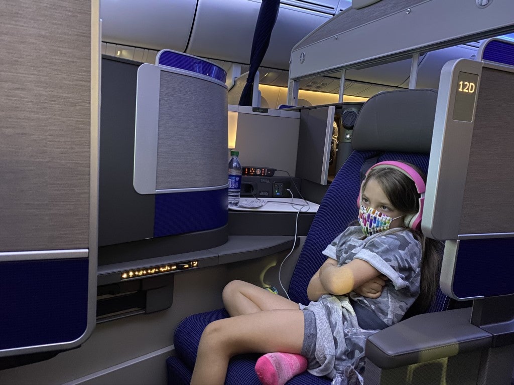 Girl in United Polaris Business Class seat with mask