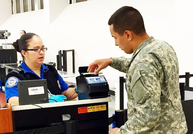 A US Navy sailor presents his travel documentation to a TSA officer A US Navy sailor presents his travel documentation to a TSA officer