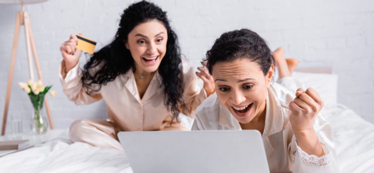 2 excited women on laptop with credit card