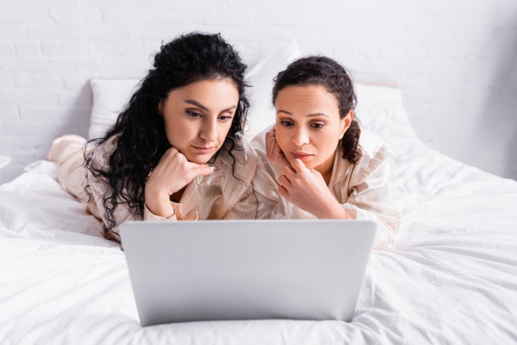 2 women on laptop in thought 2 women on laptop in thought
