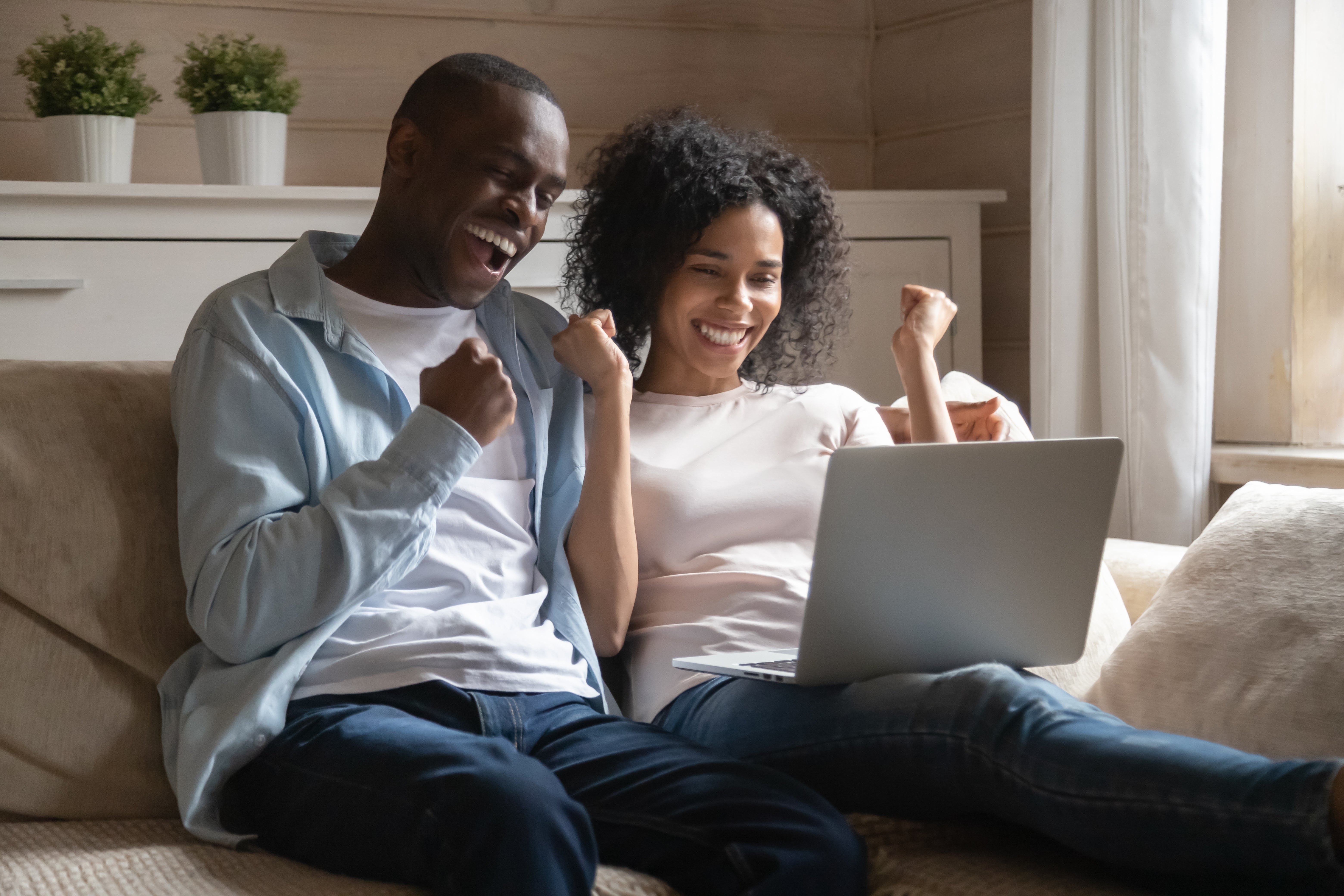 Couple on couch on laptop computer excited