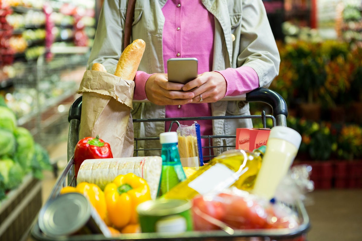 Woman on phone pushing grocery cart in supermarket