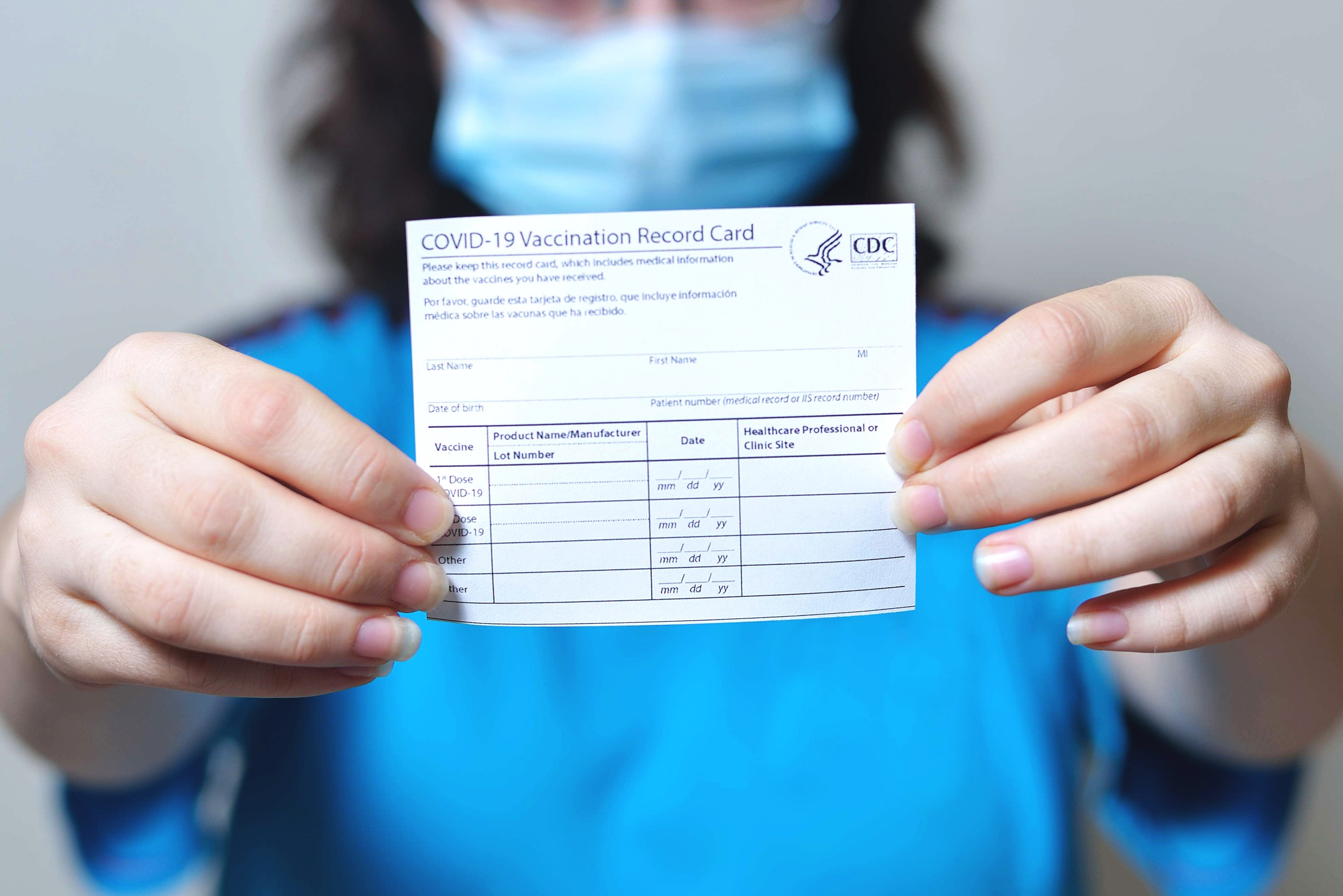 Nurse holding CDC COVID 19 Vaccine Card
