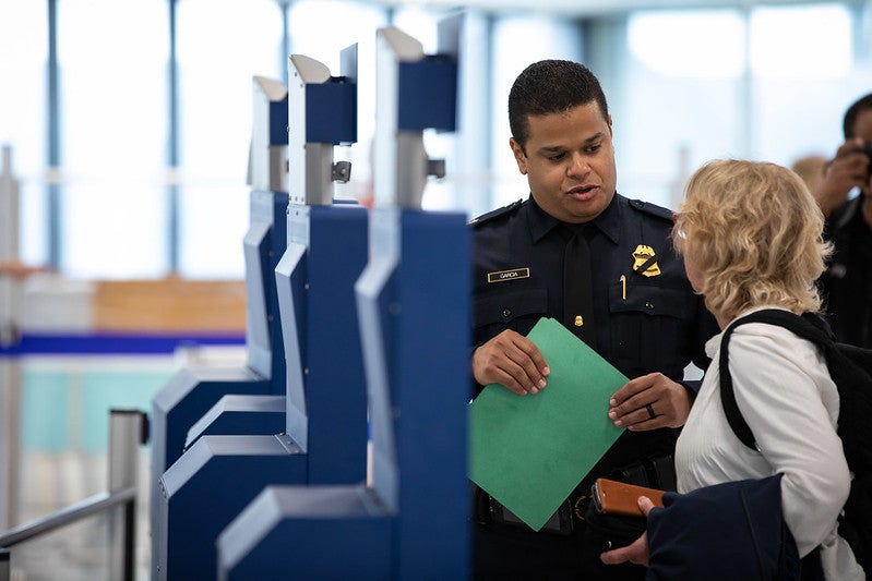 Woman using Global Entry kiosk with CBP agent