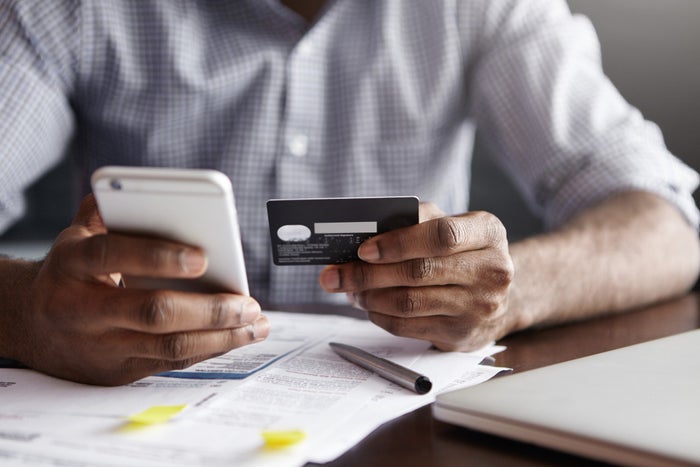 Man paying bills on cell phone with credit card