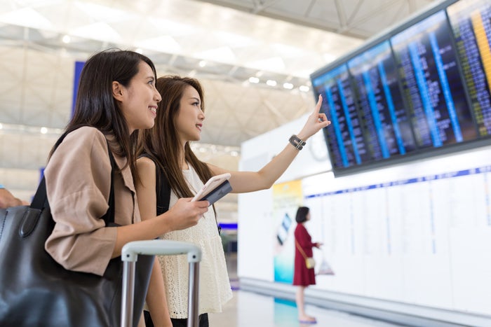 friends at airport looking at departure board friends at airport looking at departure board