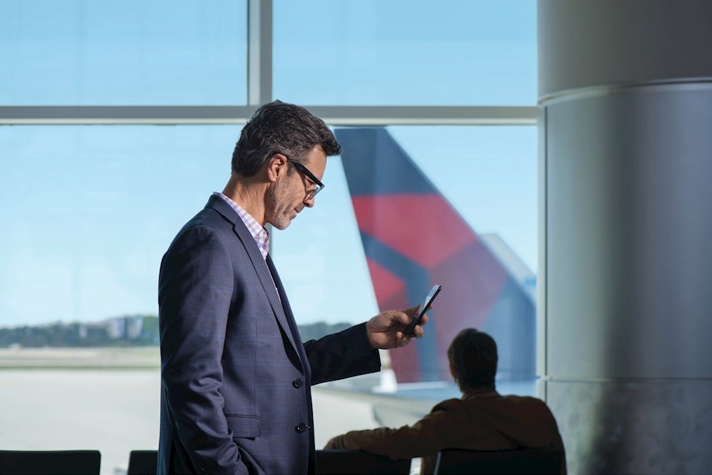 man using fly delta app in airport