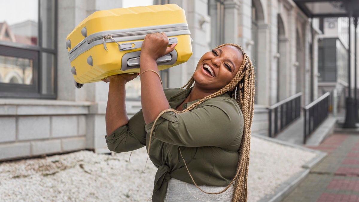 woman lifting her yellow luggage