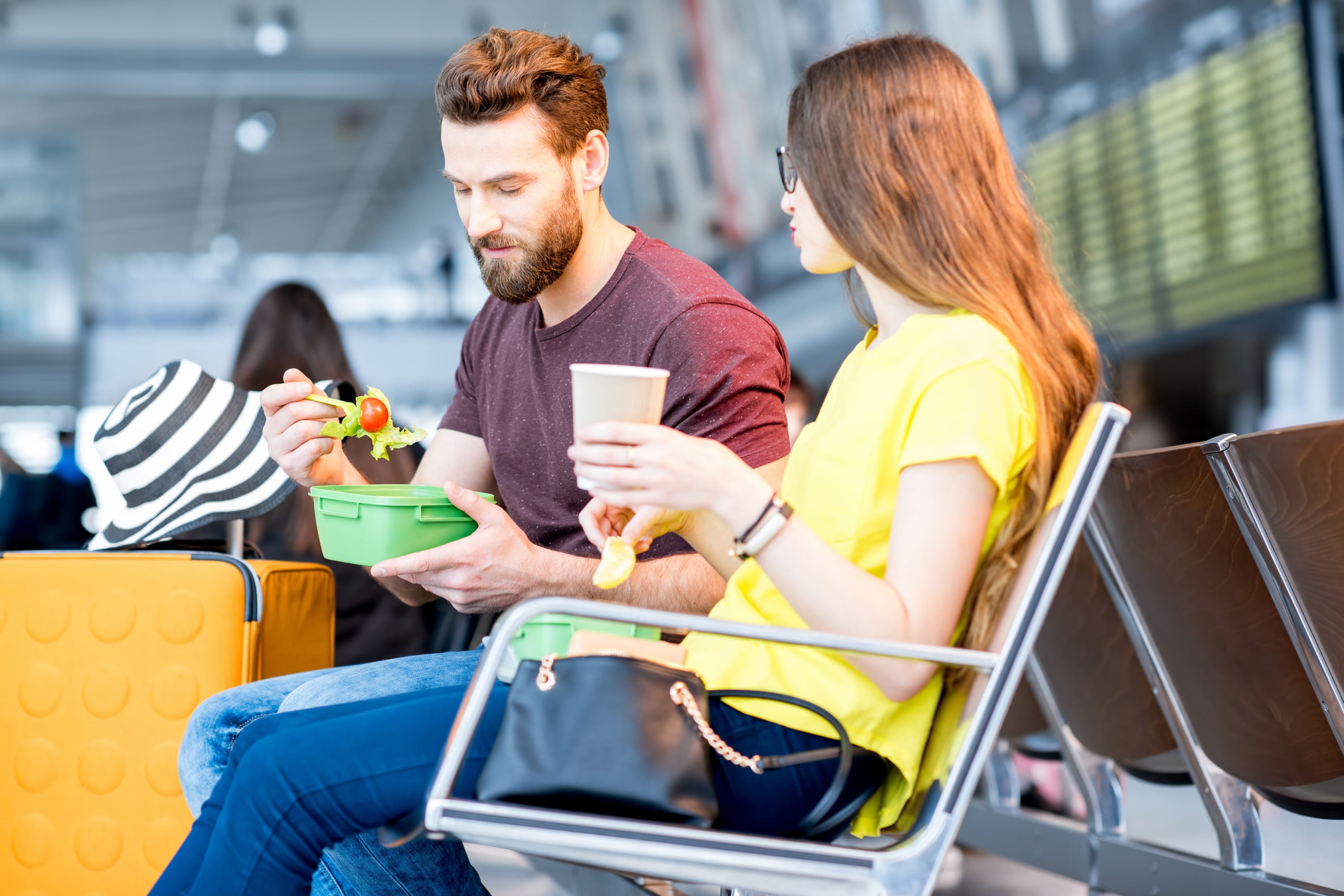 Couple eating drinking at airport looking down