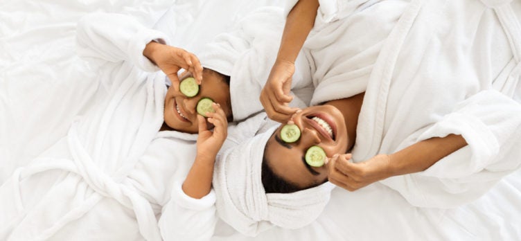 Mom And Daughter In Bathrobes Lying With Cucumber Slices On Eyes