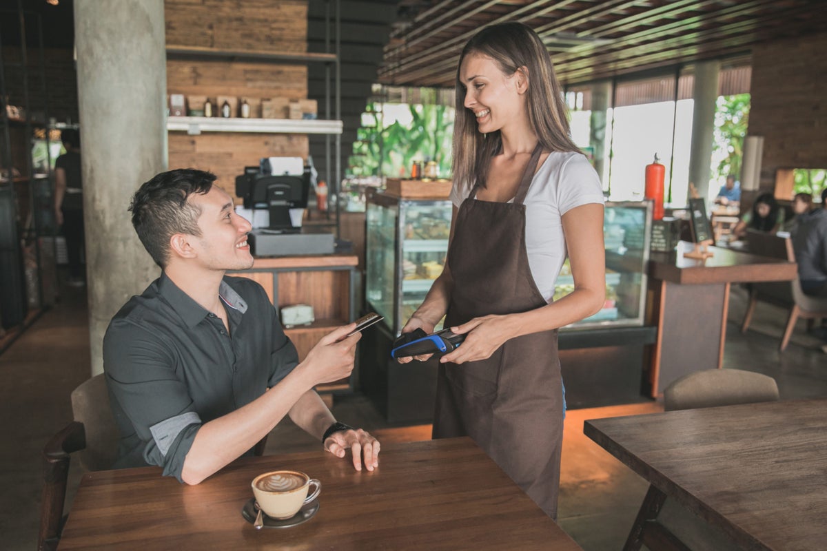 Customer paying his bills using credit card, assisted by waitress