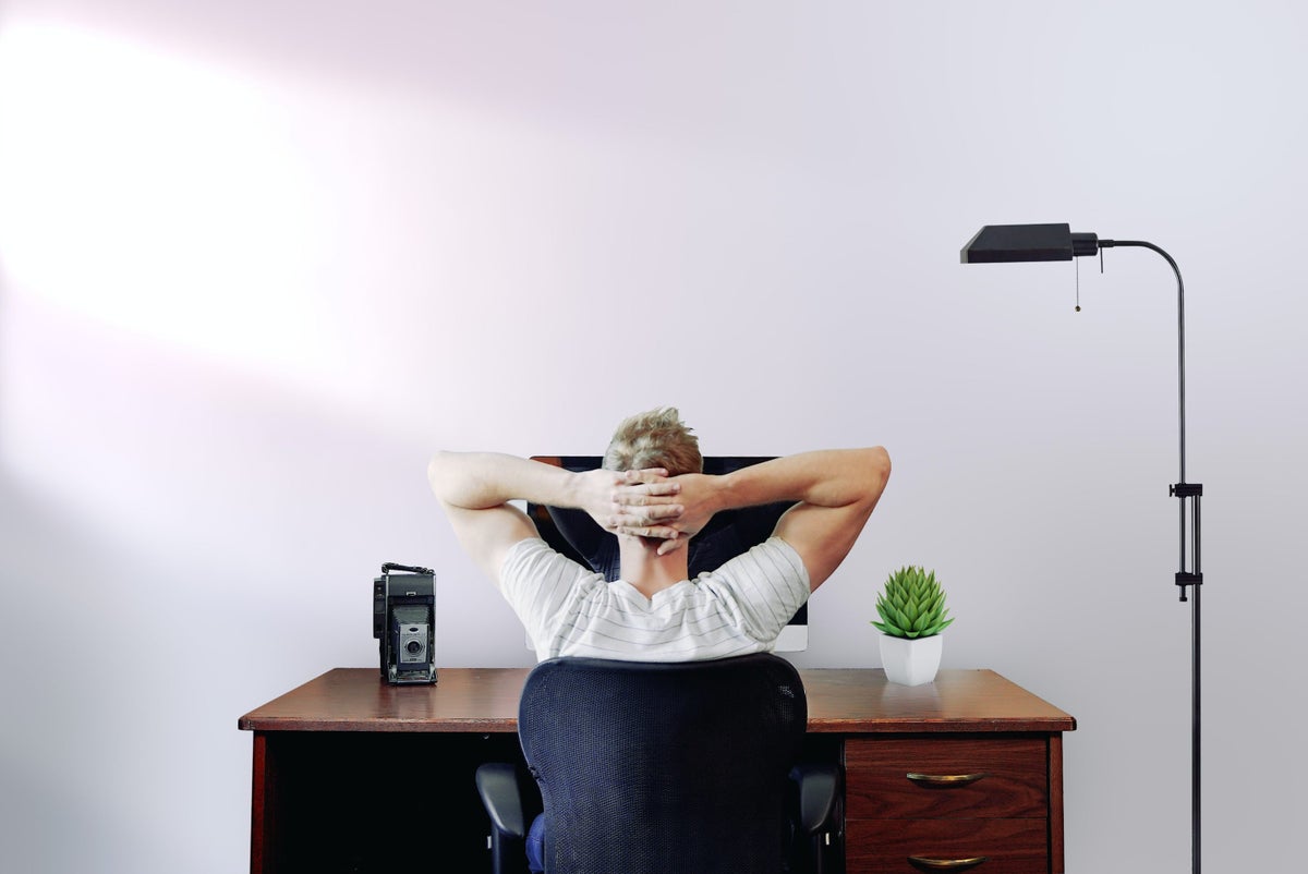 Man thinking with hands behind his head sitting at desk