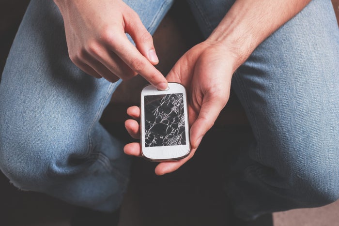 Man touching smashed broken phone Man touching smashed broken phone