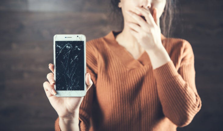 Shocked woman with smashed broken phone