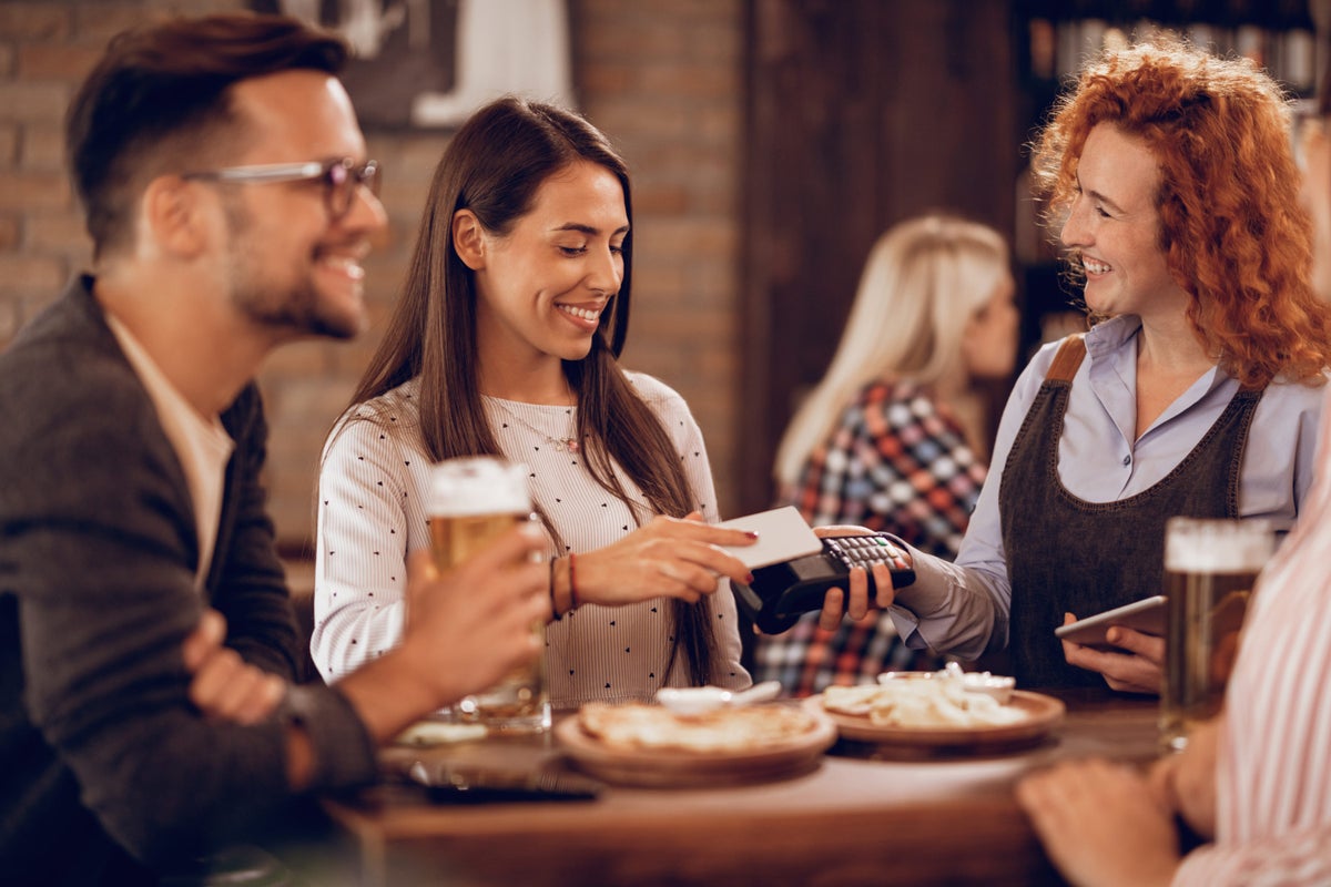happy woman paying waitress via contactless smart phone payment bar