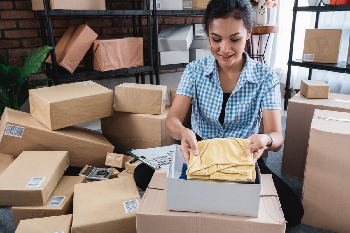 Young woman packing of clothes put on the boxes to be shipped in her office