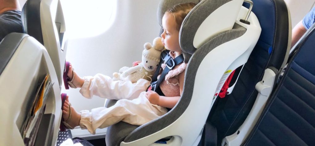 Child in Clek car seat on airplane