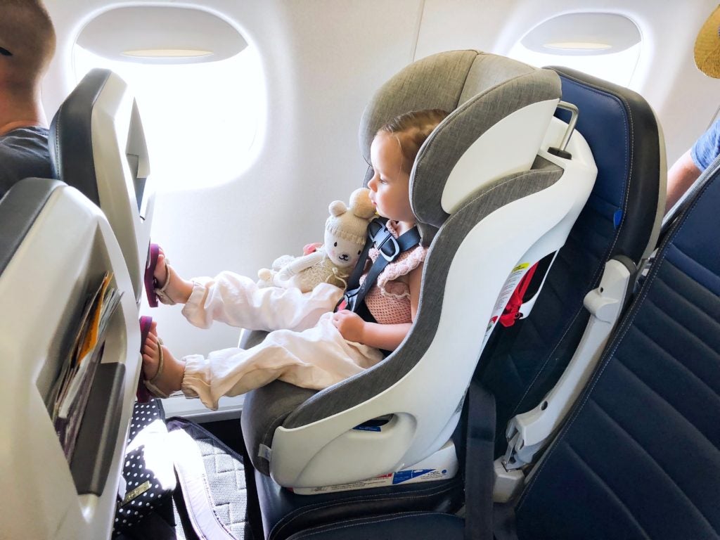 Child in Clek car seat on airplane