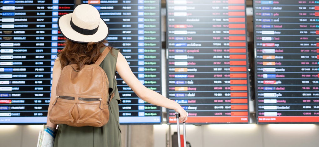Female traveler looking at airline departure board at airport
