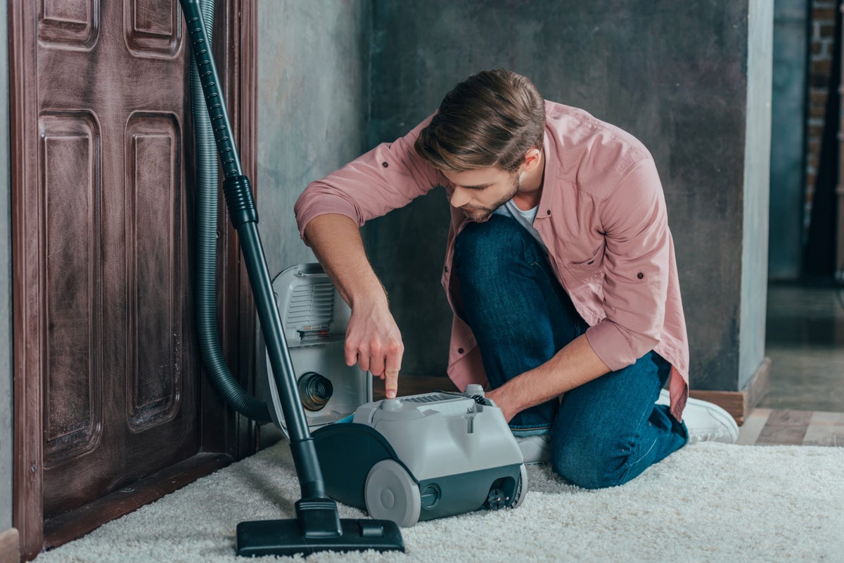 Man attempting to fix a broken vacuum