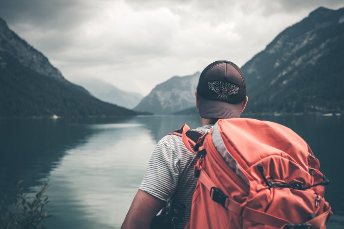 Traveler with backpack looking across lake