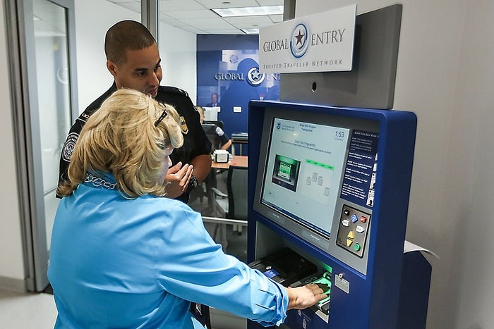 Woman using Global Entry kiosk CBP Global Entry Enrollment Center fingerprints