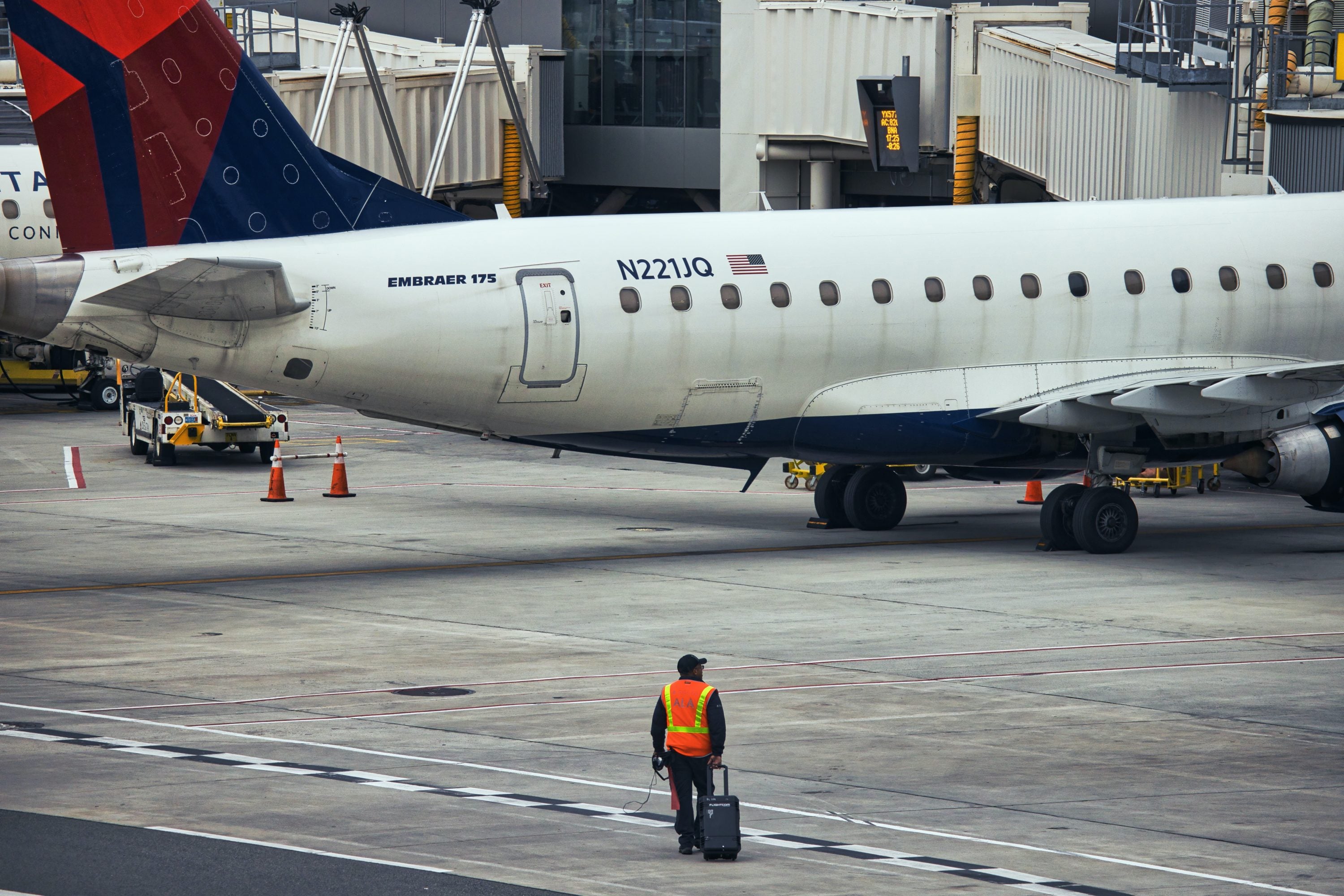 Delta aircraft with airport employee walking on the ground