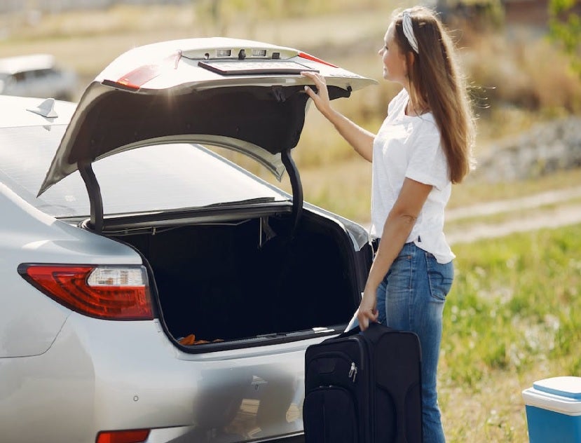 Woman loading bag in car trunk