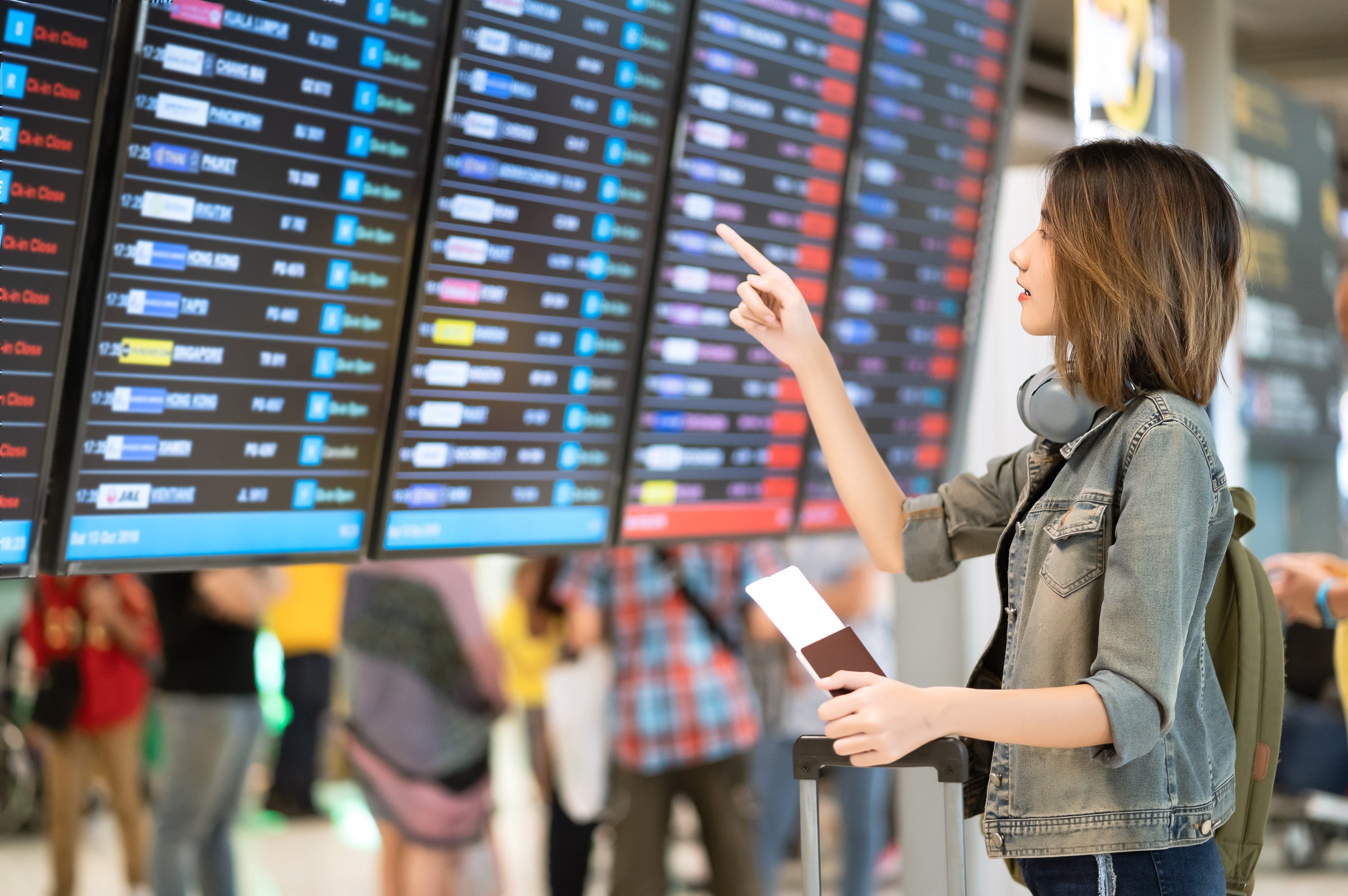 Woman pointing at airport flight departure board